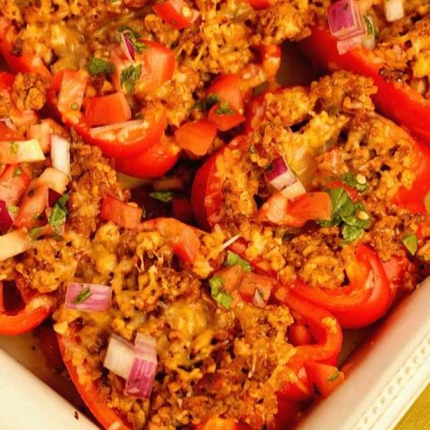 Skinny Taco Stuffed Peppers make a great high-protein, low carb meal prep idea! They are filled with taco flavor and topped with tomatoes, red onion, cilantro, and shredded cheese.